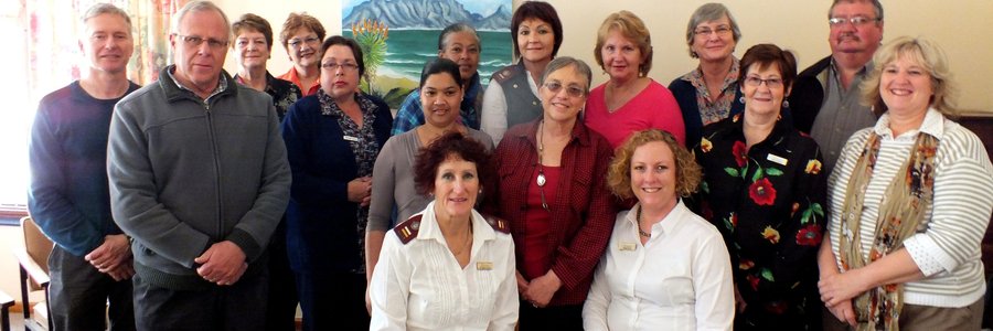 ‘n Deel van die Hospice seminaar-gangers in Herberg-aan-See se sitkamer, met voor die seminaar-aanbieders, Suster Gerna van der Riet en Fransil Kotze